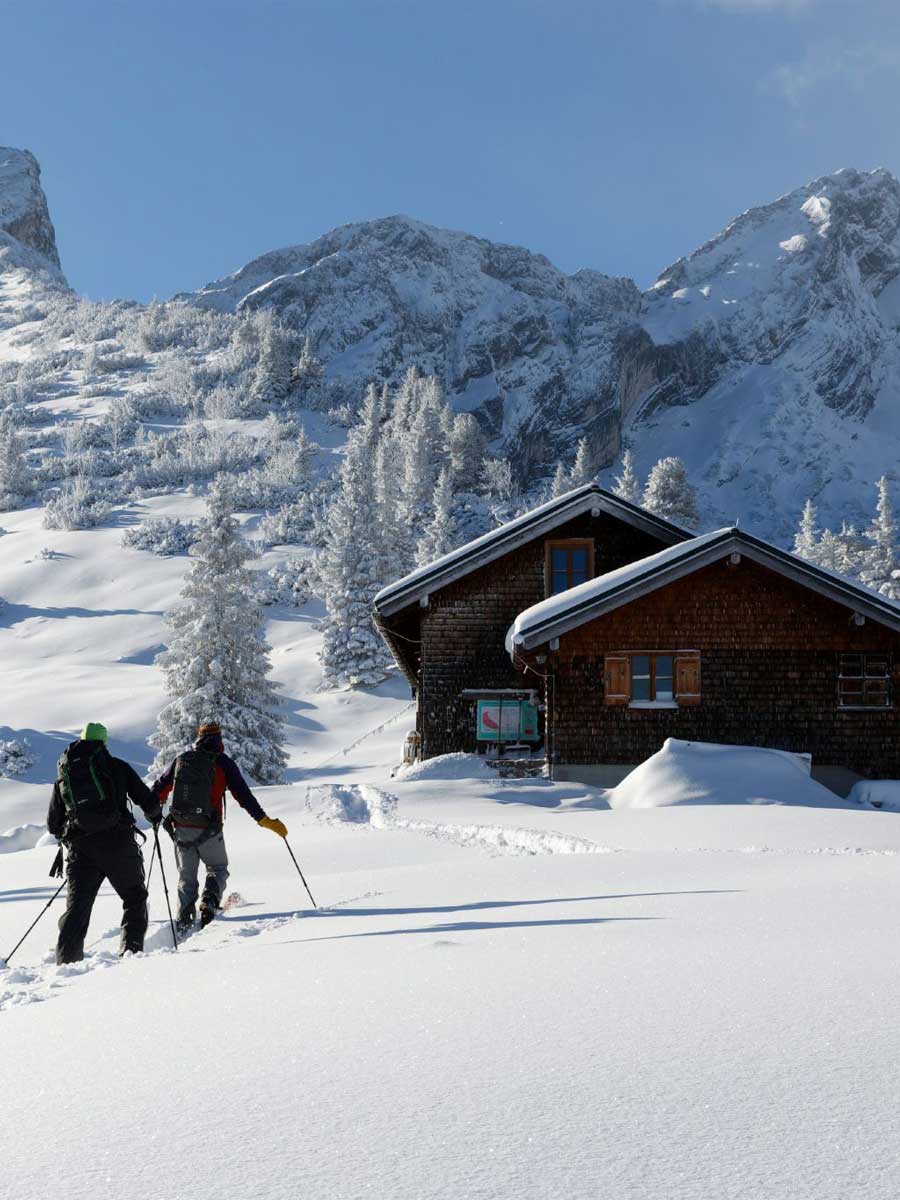 Skitourengeher vor der verschneiten Stuibenhütte im Winter